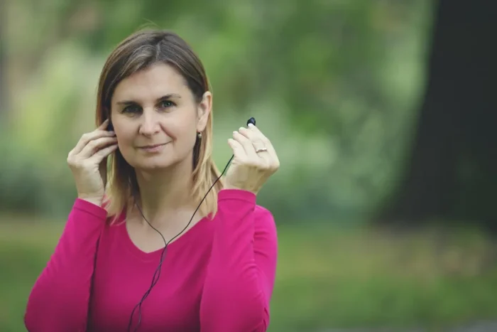 Jóga proti stresu a úzkosti. Žena si nasazuje sluchátka a chystá se na audio jógu.